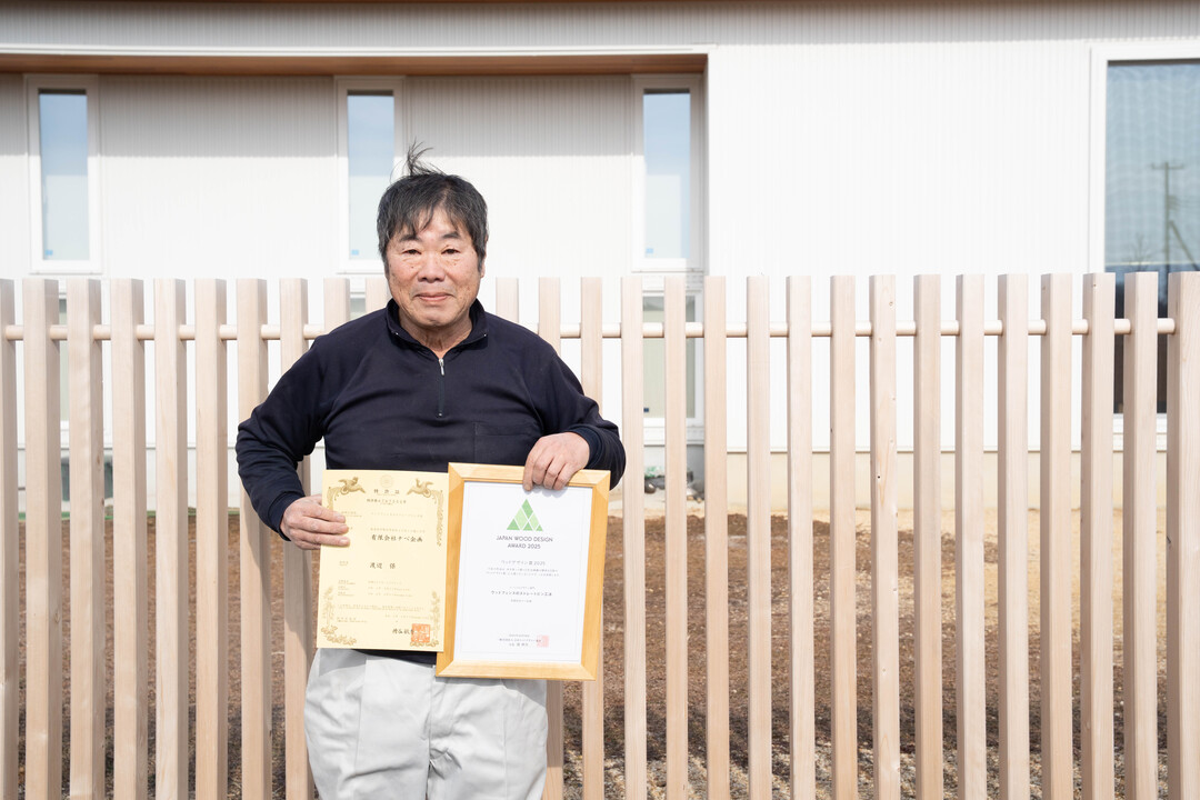 特許証とウッドデザイン賞の証書を手にする渡辺さん。2025年の森邸の木塀で、ウッドデザイン賞は5度目の受賞となった