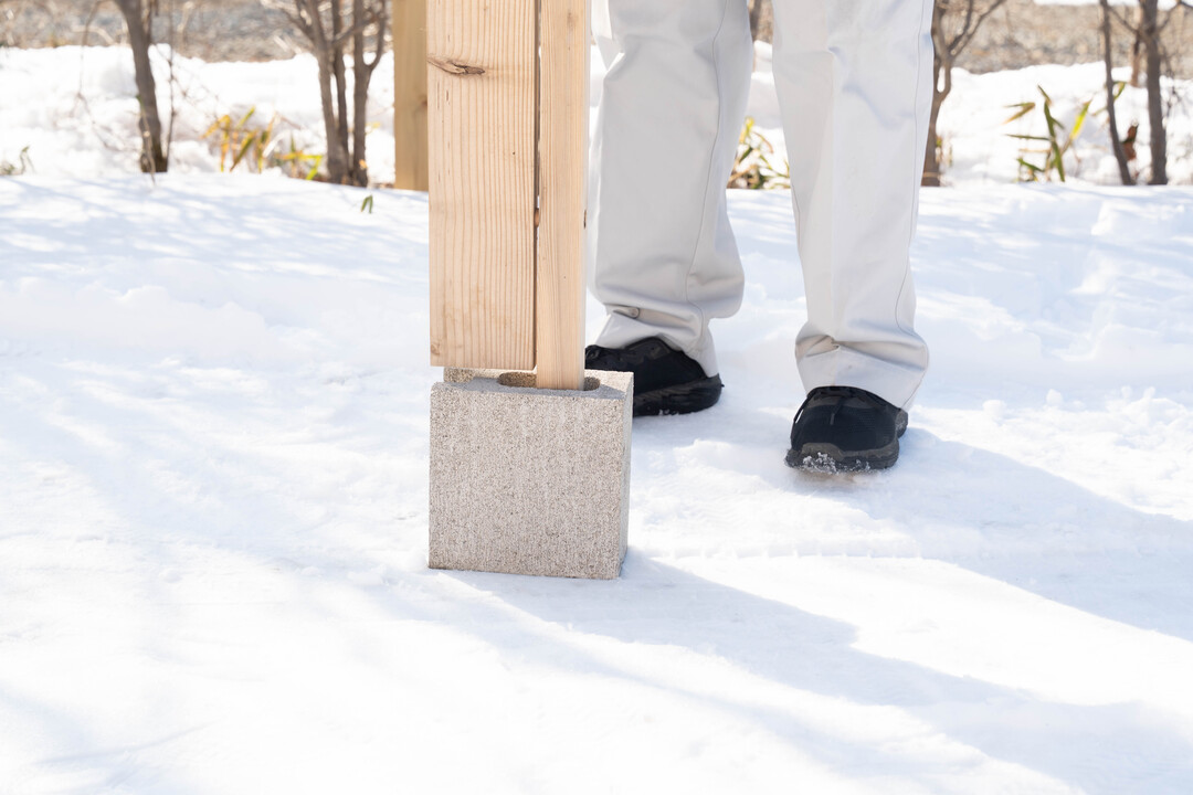 ブロックの穴に支柱を差す様子を、渡辺さんがデモンストレーション。穴の幅5cmに合わせた支柱は4.5cm角。<br>「ブロックの基礎を利用した背の高い目隠し木塀は、日本初だと思います」（渡辺さん）